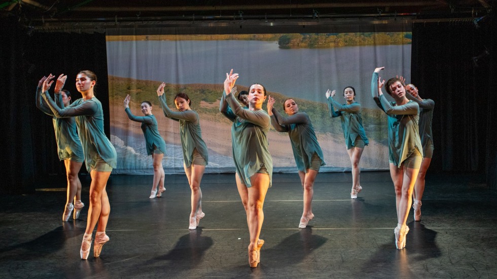 A group of ballet dancers with their arms crossed in front of them.