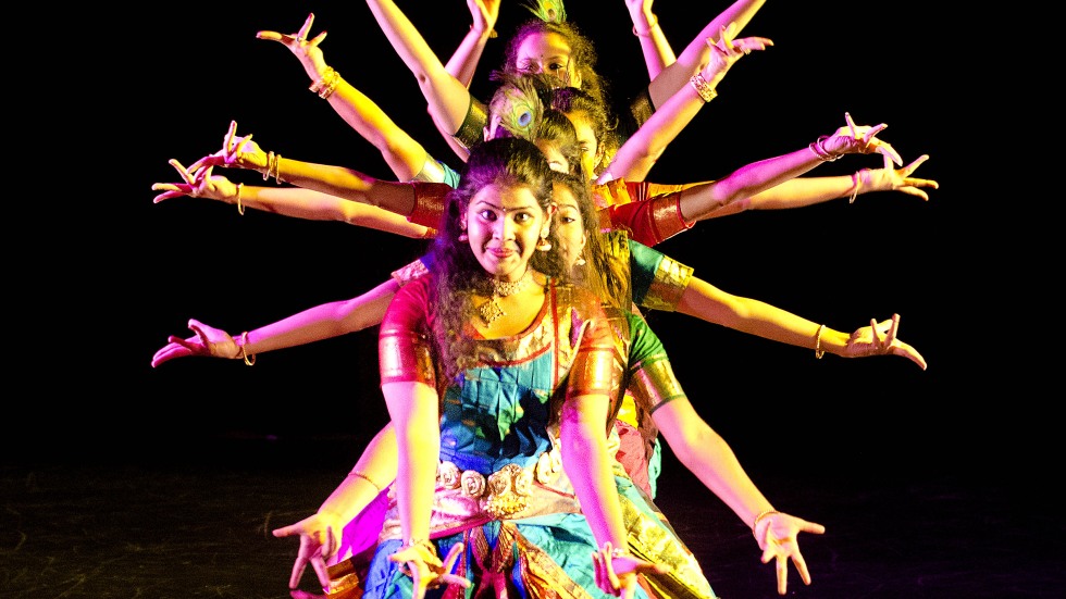 A group of dancers in colorful dress and light creating a silhouette with their arms and legs