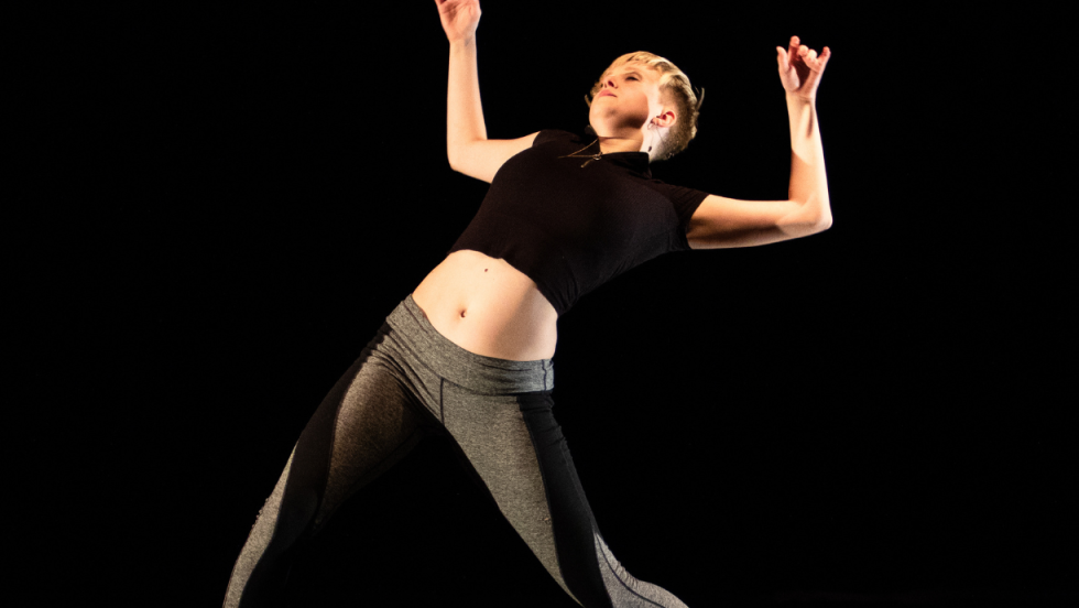 A female dancer leaning back with her knees bent, in a dance. 