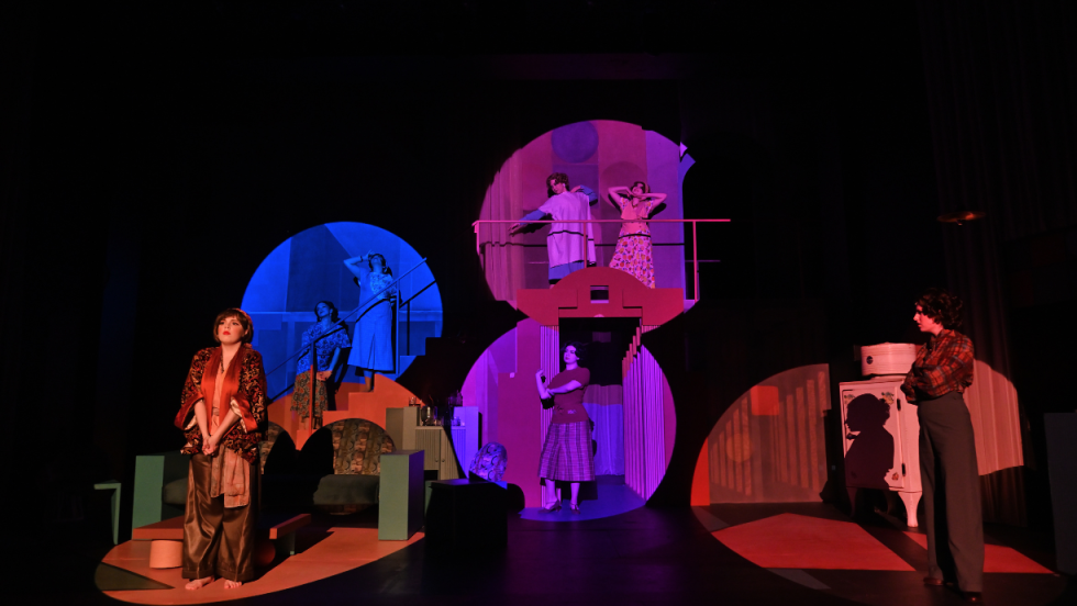 7 women in various colorful spotlights. 