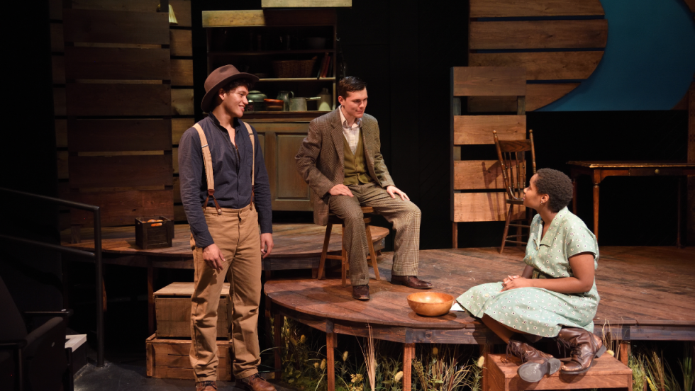 Two men talking to a young woman sitting on the front steps of a porch. 