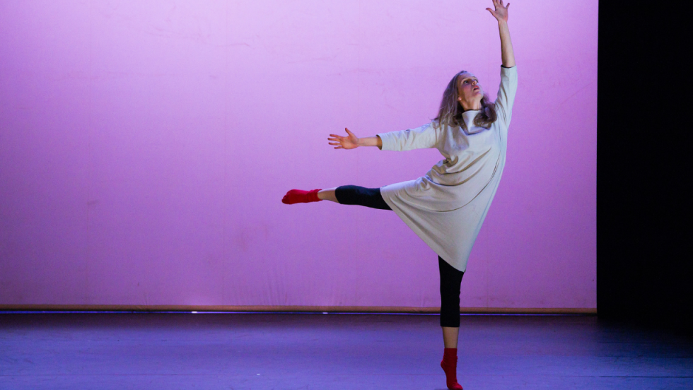 A dancer balancing on one leg with an arm stretched upward above her head. 