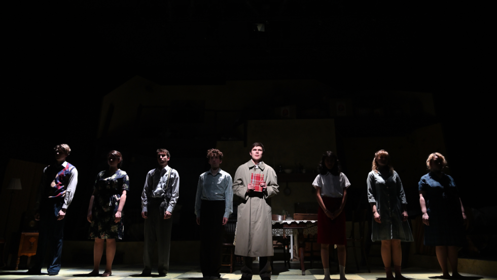 8 people standing shoulder to shoulder, the spotlight is on the man in the middle of the group. 