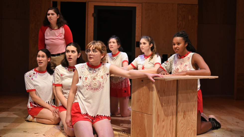 7 young women kneeling on the floor looking outward