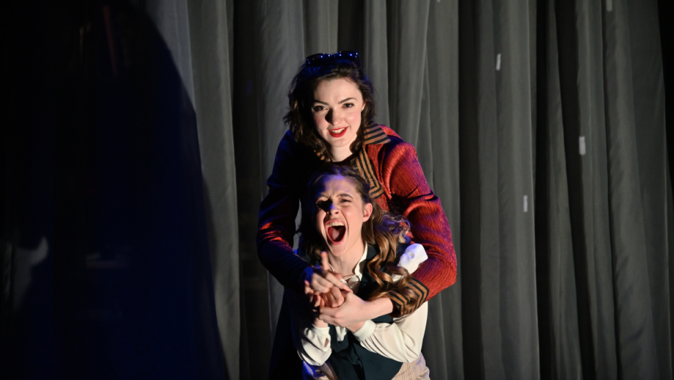 A young woman embracing a woman knelt down in front of her. 